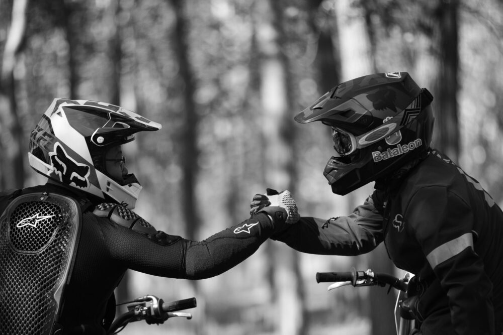 CSE face à un PSE — image en noir et blanc de deux cyclistes de compétition se serrant la main avant le départ, symbolisant la solidarité et la préparation collective face à l’épreuve.