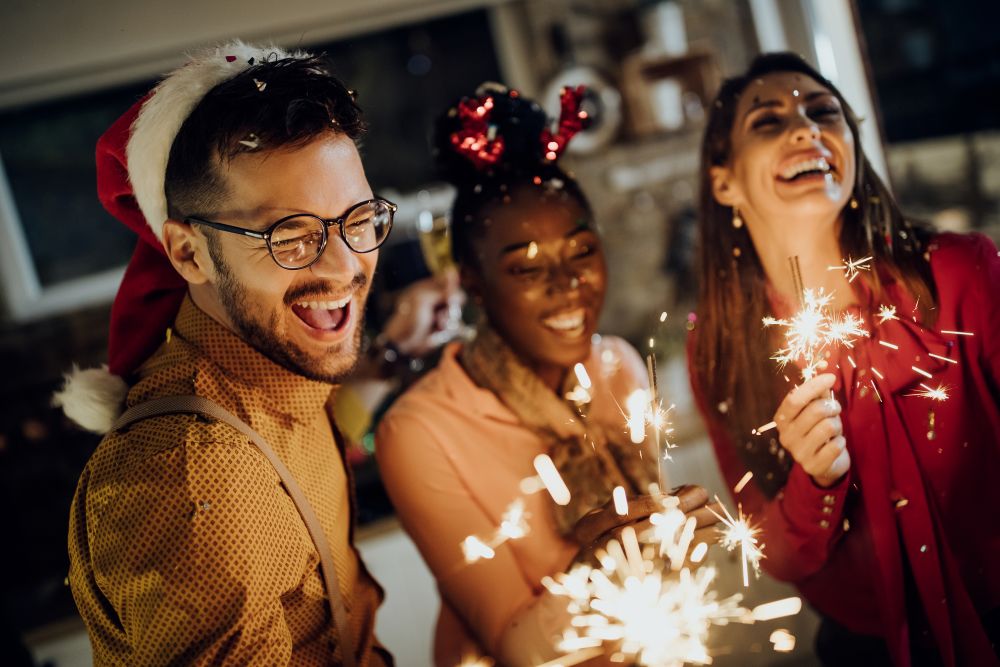 Trois personnes heureuses ouvrant des cadeaux à Noël, illustrant l'utilisation des chèques cadeaux CSE pour les événements autorisés en 2025